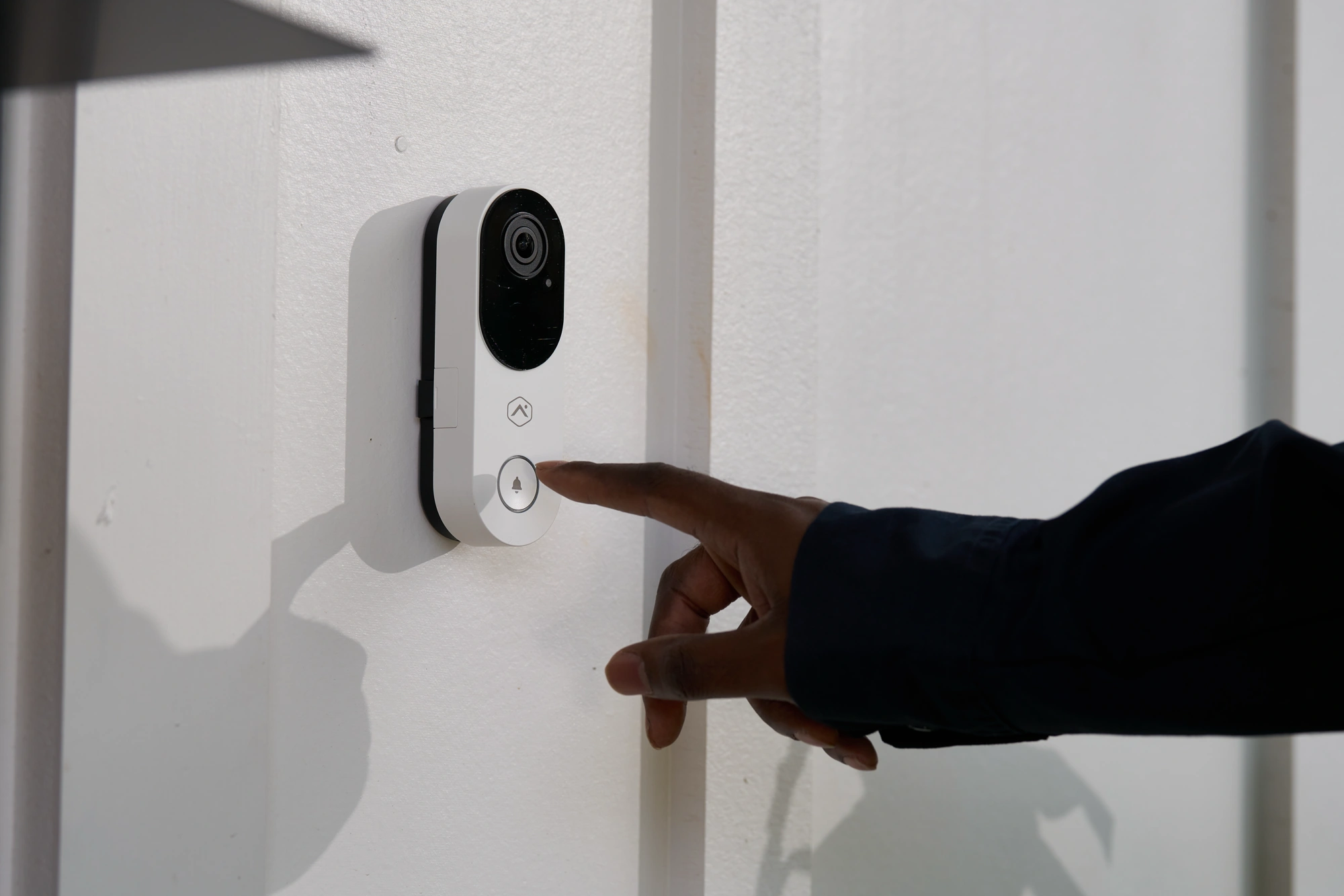 Visitor pressing a white Alarm.com ADC-VDB775 video doorbell